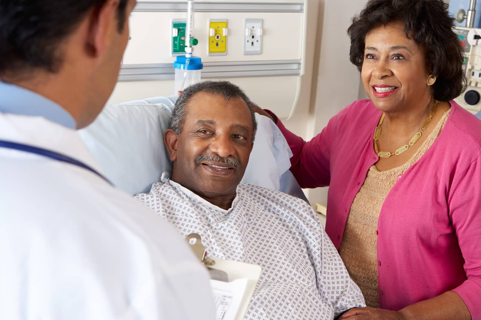 A cardiologist speaking with a hospitalized patient and his wife